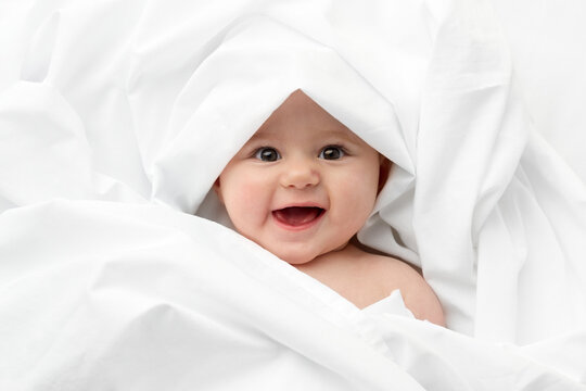 Smiling baby face wrapped in white sheet