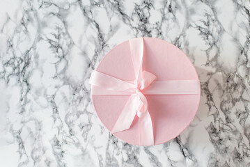 Round pink gift box on light marble background