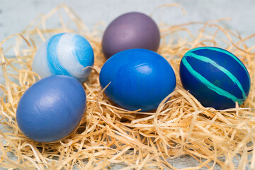 Fototapeta na wymiar Blue decorated easter eggs in straw nest