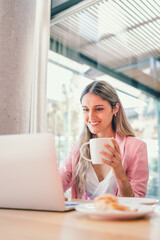 Peaceful smiling millennial business woman using laptop and having a video call in modern workplace