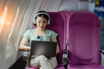 Asian female using laptop and sitting in airplane, Business traveling and technology concept.