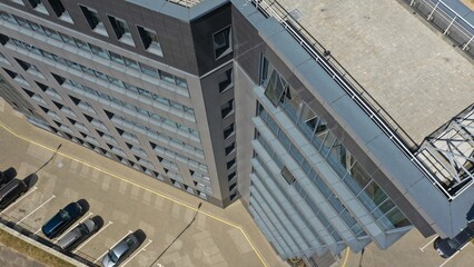 The drone takes pictures of a tall building from top to bottom. Top view of a skyscraper from a quadcopter. All floors of a skyscraper. Modern office building, sunny side view.