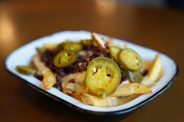 French fries with jalapeno and fried onion on top on a white plate restaurant. Section B.