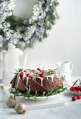 Christmas chocolate bundt cake. Traditional Christmas fruit cake with white glaze, cranberries and rosemary on white stand with Christmas decoration. Winter baking at Xmas or New Year. Copy space.