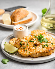 Baked cauliflower steaks with sauce on white plate, selective focus