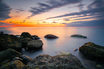 Sunset at Sea, stones on the shore, Amazing perfect pink dreamy looking sunset. Smooth water