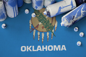 Oklahoma US state flag and few used aerosol spray cans for graffiti painting. Street art culture...