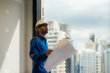 Arab civil engineer wearing safety uniforms workwear  Standing holding a blueprint of a real estate...