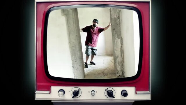 A transmission on an old retro tv set: a perplexed man moving in slow motion into an oblique room, exploring its weirdness. Funny bizarre shot.
