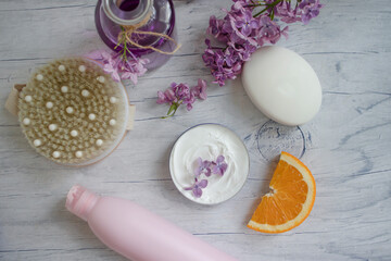 Massage brush, cream, lilac flower, orange on a light background