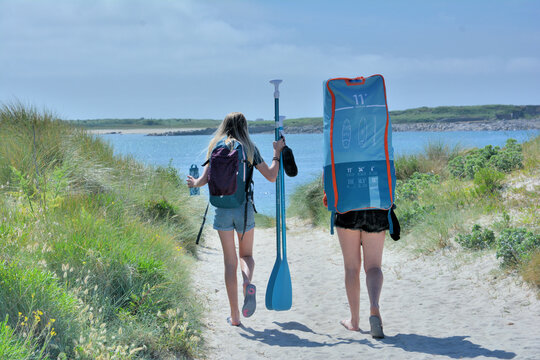 Jeunes filles qui vont faire du paddle sur une plage de Bretagne