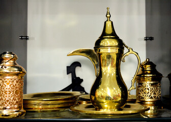 Fototapeta na wymiar Islamic Ramadan fasting month decorations of brass jugs and festive lanterns, lamps or Fanous on shelf as a festive icon for Muslims, festive celebration of the holy month background, selective focus