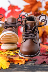 children's brown boots  for  boy, against the background of autumn leaves. Photo in motion.