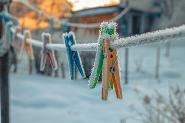 Clothes pegs hung on a clothesline in winter. Pegs for clothes with ice crystals in winter on a...