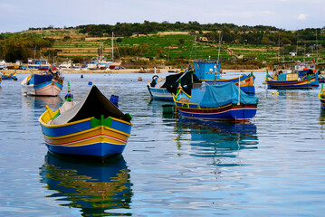 Fototapeta na wymiar Traditional fishing boats luzzu in Marsaxlokk village in Malta, painted in bright colours – blue, red and yellow. The bow has a pair of eyes.