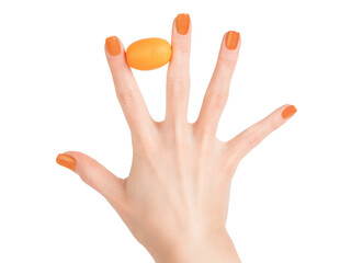 Woman hand with perfect skin and orange nail polish holding small orange citrus fruit between the...