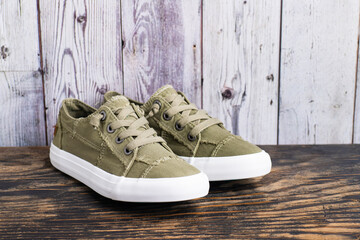 retro hipster sneakers with white laces stand against a gray wall on the floor. Banner. Space for...