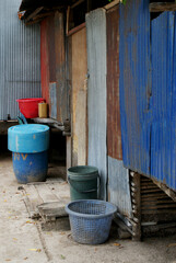 Colourful plastic barrels in front of a metal wall, background with various textures and patterns, rusty and shabby still life composition