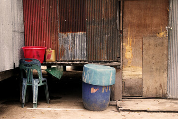 Obraz premium Colourful plastic barrels in front of a metal wall, background with various textures and patterns, rusty and shabby still life composition