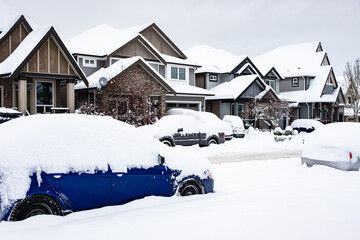 A car under the snow. Winter urban scene in Canada. Vehicles covered with snow in the winter blizzard in the parking