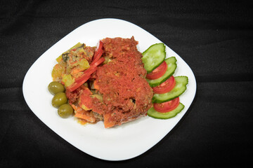 Potatoes and meat with vegetables in tomato sauce on a white plate
