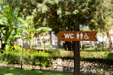Obraz premium sign toilet in the park, sign to the WC and for the disabled toilet among the trees
