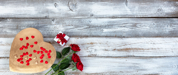Fototapeta na wymiar A large golden heart and other gifts including red rose flowers on white rustic wood for a happy Valentines day holiday setting