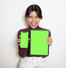 Naklejka premium A woman holding a smartphone and a laptop while smiling on the white background