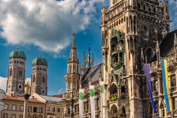 Fototapeta na wymiar Die im Stil der Neugotik gestaltete Fassade des neuen Rathaus mit Rathausturm in der Altstadt von München in Unteransicht vom Marienplatz aus gesehen bei schönem Sommerwetter und blauen Himmel mit den