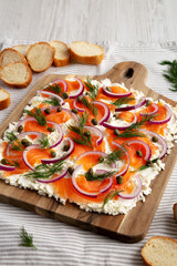 Homemade Cream Cheese Lox Bagel Board with Salmon on a white wooden background, low angle view.