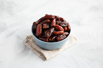 Pitted Organic Dates in Bowl on gray background, side view.