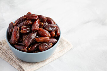 Pitted Organic Dates in Bowl on gray background, low angle view. Copy space.