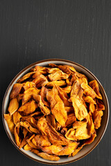 Delicious Organic Dried Mango Fruit in a Bowl on a black background, top view. Flat lay, overhead, from above. Copy space.