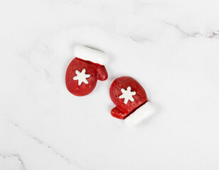 Cute sweets covered with colored icing sugar, in the form of Christmas red mittens with a snowflake. White background. Top view