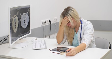 The doctor is very exhausted by a lot of work. A woman veterinarian sits at a table resting her...