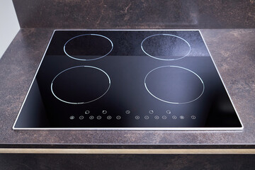 Grey countertop with black glossy built in ceramic glass induction or electric hob stove cooker with four burners in dark empty modern contemporary flat design loft kitchen interior. - obrazy, fototapety, plakaty