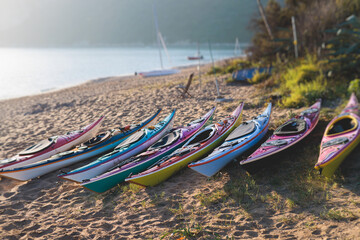 View of colorful kayaking equipment on a sandy beach, process of kayaking by the Ionian sea beach, with canoe kayak boat paddling, process of canoeing, vibrant summer picture, Greece, Corfu Island