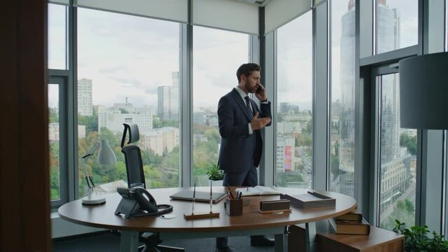 Annoyed entrepreneur talking phone gesturing emotionally standing modern office