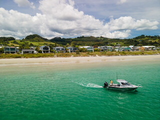 Fototapeta na wymiar Amphibious fishing boat with Sea Legs driving from beach out to sea along New Zealand coastal town in the Coromandel Peninsula