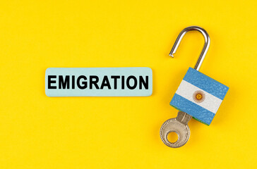 On the yellow surface is an open lock with a key and a sticker with the inscription - Emigration