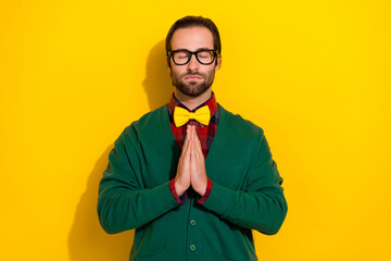 Naklejka premium Photo of young funny closed eyes gentleman wear stylish bowtie hands together pray for ukrainian peace stop war isolated on yellow color background