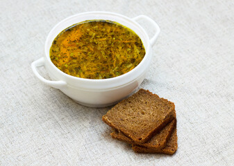 Vegetable soup and three pieces of bread on a table.