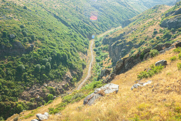 Automobile road running between high mountains in summer. top view of the road medu high mountains from both sides