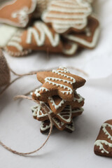 christmas gingerbread cookies on a white table, shape of a star cookies, pyramid of Christmas cookies,cookies painted with white icing, crispy homemade sweets, brown cookies 