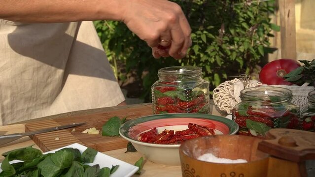 The woman makes a homework - dried tomatoes with fresh basil, garlic and salt. The process of making dried tomatoes 