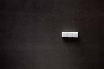 Three white cubes are placed on a black background. Material for composing text.
