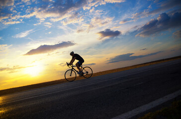 Fototapeta premium Young sports man cycling with bicycle on the road in summer