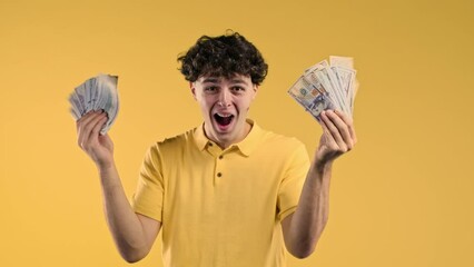 Rich excited man with cash money - USD currency dollars banknotes on yellow wall. Symbol of jackpot, gain, victory, winning the lottery - Powered by Adobe