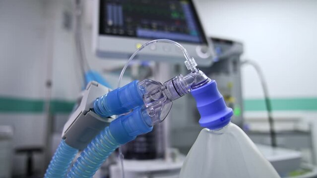 Thick tubes connected to inflating ambu bag. Close up. Lung ventilator machine working at blurred backdrop.