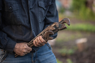 man holding old pipe wrenches in his hands